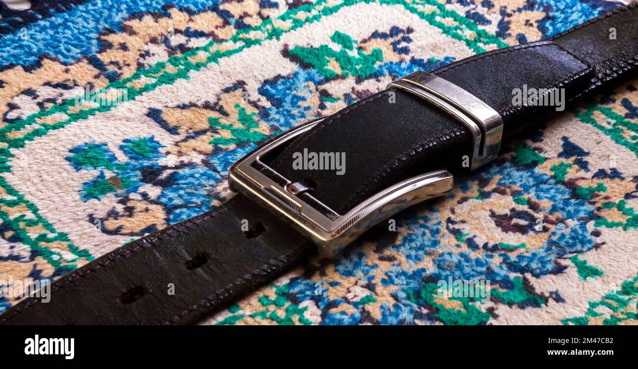 Black men`s belt stylish, placed on a carpeted Stock Photo